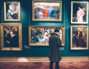 Art gallery visitor looking at vintage paintings